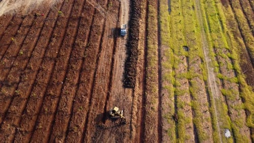 Aerial view of a wheel loader excavator with a backhoe loading sand into a heavy earthmover