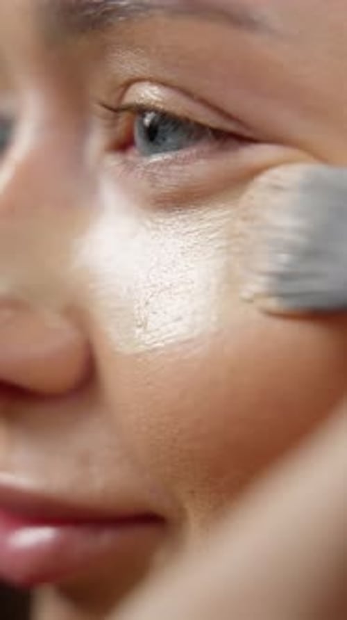 Makeup Artist Carefully Applying Liquid Foundation with Professional Brush Smoothing Skin Surface