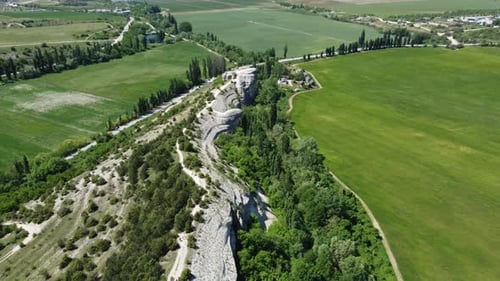 Aerial View of Lush Green Farm Field at Spring Sunny Day with Rocky Cliffs in the Distance Beauty of
