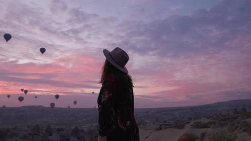 Woman Gazing at Hot Air Balloons at Sunrise