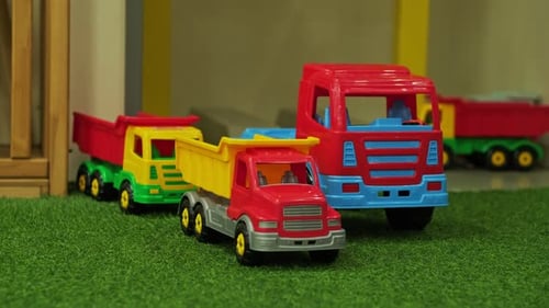 Farbenfrohe Spielzeugtrucks auf einer grasbewachsenen Oberfläche in einer spielerischen Umgebung für lustige Aktivitäten für Kinder