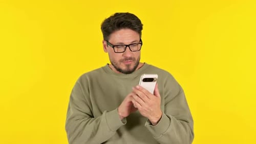 Man Using Smartphone on Yellow Background