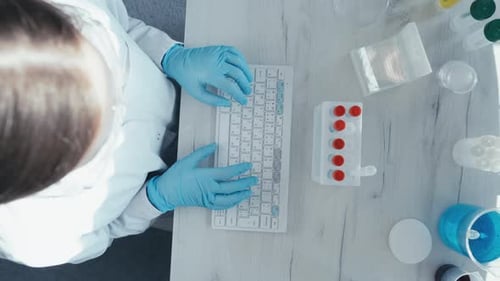 Scientist Typing Data in Lab Overhead