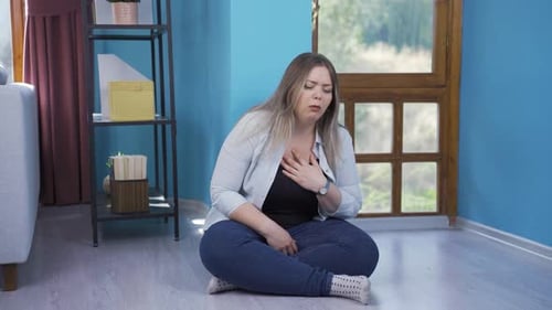 Jeune femme malade toussant appuyée contre un mur. Désespéré.