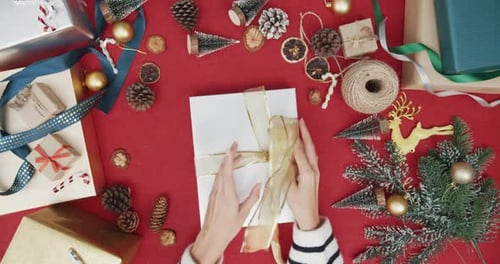 Top view of girl hands unpacking present gift box winter christmas decorations on red background.
