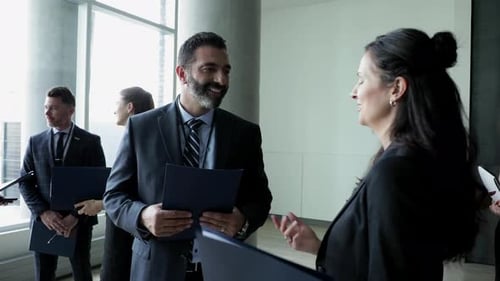 Business professionals gather in office space holding documents