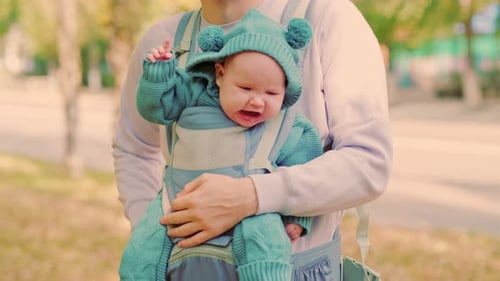 Newborn Baby with His Young Father in a Sling Close Up