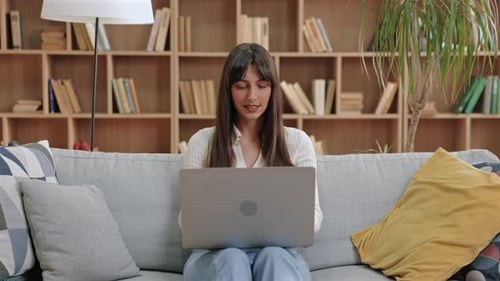 Young Adult Female Uses Laptop on Couch