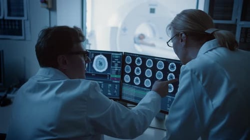 In Control Room Doctor and Radiologist Discuss Diagnosis while Watching Procedure and Monitors Show