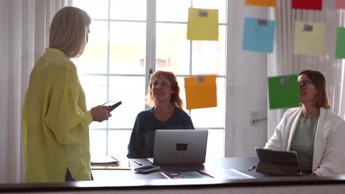 Creative businesswomen discussing a project in a modern office, using digital tablets and laptops, w