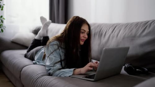 Young Woman Using Laptop While Relaxing on Couch
