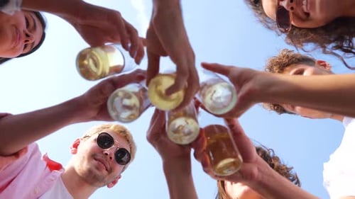 Carefree Friends Enjoying Party on Rooftop Terrace While Holding Bottles with Beer While Clinking