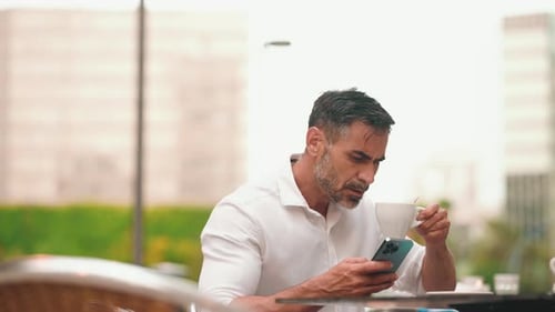 Mature businessman uses mobile phone sits on