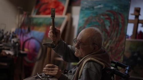 Senior Elderly Master Jeweler in Wheelchair Works in a Workshop