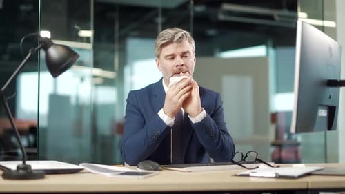 Man with Cold Blowing Nose at Desk