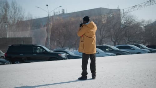 Back View Photographer Capturing Snowy City Plaza Cars Under Winter Daylight