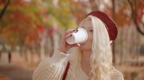 Blonde Woman Sipping Drink Walking in Forest Park, Autumn Beauty