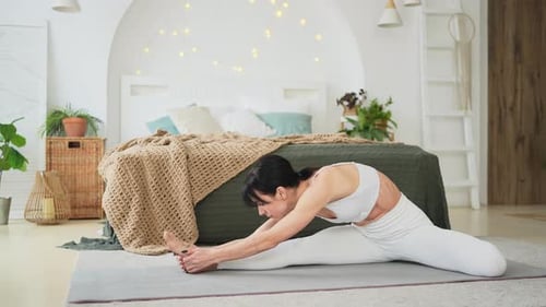 Woman Stretching Legs in Bright Bedroom