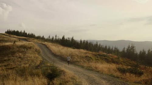 Jogger running on road in mountains. Tired runner taking rest during workout