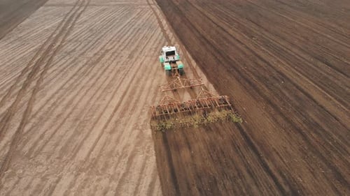Agricultural Industry Aerial View Tractor with Plough Working on a Field at Sunset Tractor Plowing