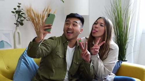 Gemischtrassiges Paar sitzt im Wohnzimmer und macht Selfie