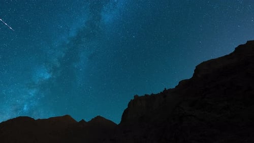Starry Night Sky with Shooting Stars Over Mountains