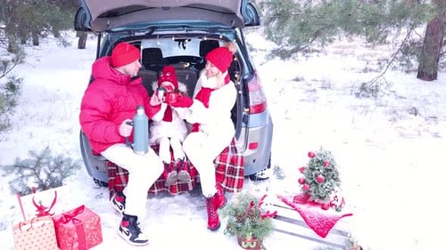 Family - father, mother and daughter cheerfully celebrate Christmas in the forest