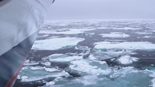 Bug eines Bootes segelt zwischen zerbrochenen Eisstücken in der kalten Arktis, Zeitlupe