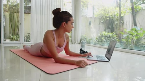 Woman Doing Plank Exercises Watching Laptop at Home