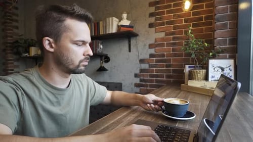 Ein konzentrierter junger Mann, der begeistert in einer gemütlichen Café-Umgebung arbeitet