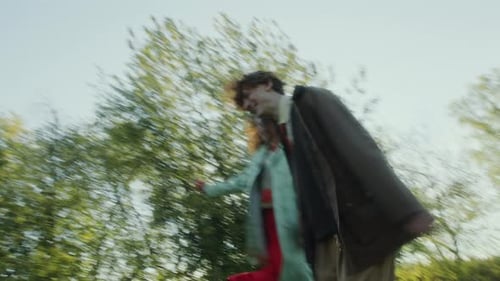 Excited Couple Holding Hands and Running through Green Meadow