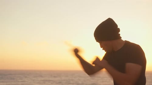 Man Shadow Boxing by Ocean During Beautiful Sunrise
