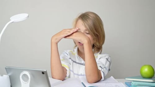 Middle School Smiling Student Boy Sitting at Desk Remote Studying Writing Book Homework and Tablet