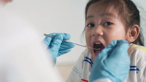 Dentist Examining Child's Teeth with Mirror