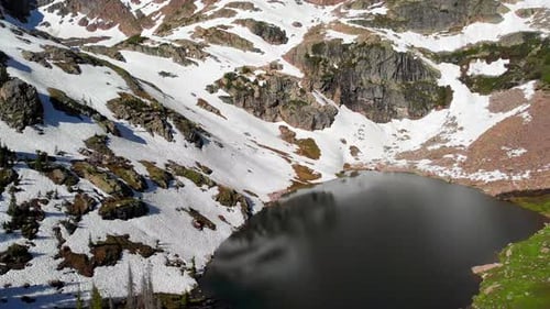 Aerial shot of lake, tilting up to reveal spectacular mountains.