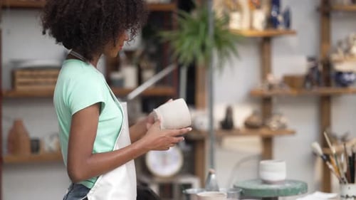 Young women is making earthenware at workshop.