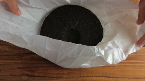 Shu Puerh cake Chinese fermented black tea on white paper with a knife