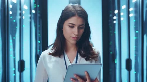 Dedicated and Focused Female Professional Working in a Data Center While Using a Tablet