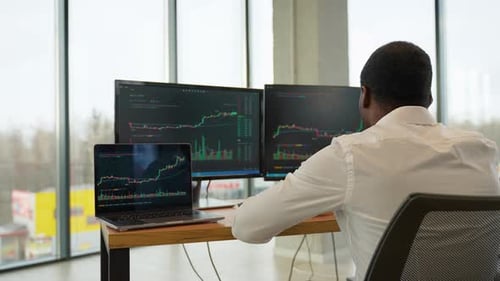 Trader sitzt vor Computern und analysiert professionell die Erstellung von Candlestick-Charts