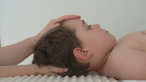Closeup Side View of Cute Five Year Old Boy Laying on Bed at Manual Therapist in Osteopath Cabinet