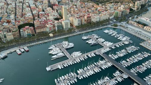 Aerial drone view of the Port of Alicante and the buildings in the city in the evening