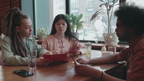 Group of Diverse Friends in Restaurant, Looking Through Menu, Discussing Order