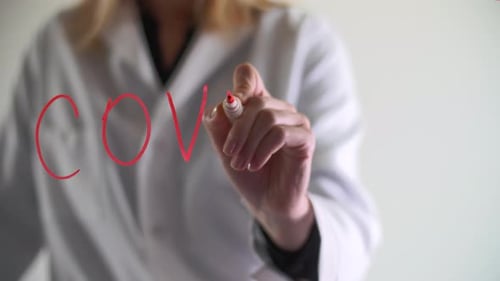 Doctor Writes COVID-19 on Clear Surface with Marker