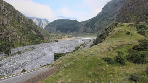 Aerial shot of river in the middle of mountains sky and cloud in the background