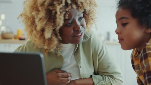 African American Kid Discussing Something on Laptop Screen with Mom at Home