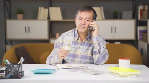 Man Counting Money and Talking on Phone Indoors