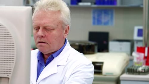 Man in Lab Coat Working at Computer