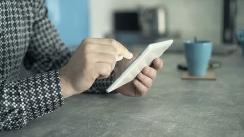 Man scrolls on a tablet at a table