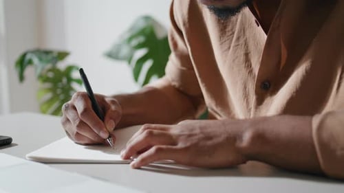 Man Writing in Notebook Indoors