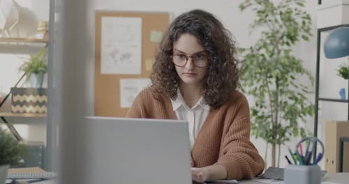 Portrait of Ambitious Young Business Lady Typing Working with Laptop at Desk in Light Office